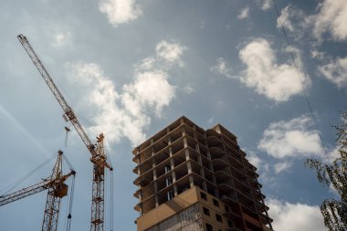 İnşaat alanında altyapısı gelişen yeni bir yerleşim yeri. Ev yapım aşamasında. Modern şehir binası vinçle inşa ediliyor.