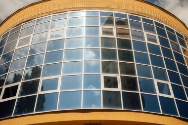 Modern ofis binasının pencereleri. Modern mimari bankası finans kulesi binası. Bulutlar ve parlak mavi gökyüzü modern bir ticaret binasının kare aynalı pencerelerine yansıyor.