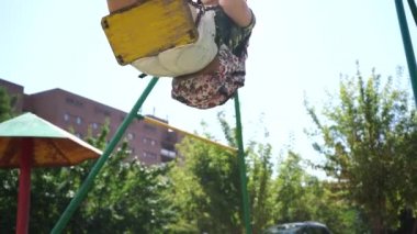 Günlük giysiler içinde genç bir kadın parkta salıncakta sallanıyor.