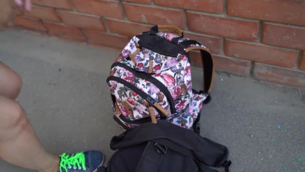 Eine junge Frau nimmt auf der Straße ein Tagebuch aus einem Rucksack. — Stockvideo