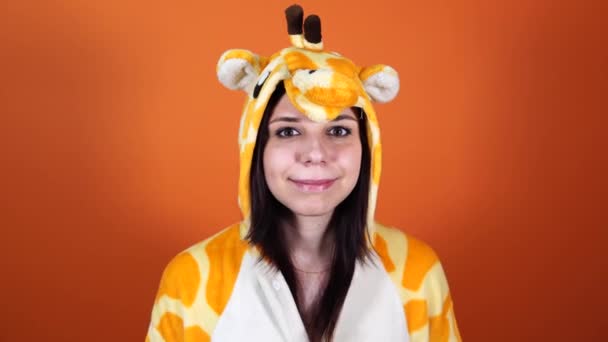 Pyjamas in Form einer Giraffe. Emotionales Porträt einer Frau auf orangefarbenem Hintergrund. Verrückter und lustiger Mann im Anzug. Animateur für Kinderfeste. Halloween-Party-Kostüm — Stockvideo