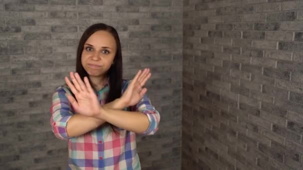A beautiful young woman in a plaid shirt nods her head in protest on a brick background. A woman makes a gesture of refusal. portrait of a young woman. body language and gestures. she nods – Stock-video
