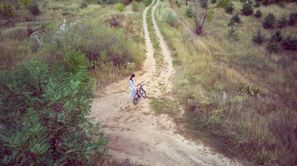 Mladá žena projíždí krajinou na kole. Letecký pohled na cyklistiku. Koncept zdravého životního stylu. — Stock fotografie