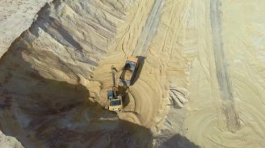 Ağır bir makine, kazıcı ve kamyon kum ocağında çalışıyor..