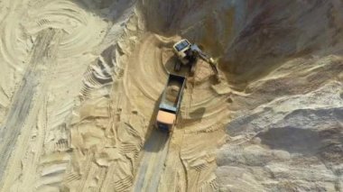 Ağır bir makine, kazıcı ve kamyon kum ocağında çalışıyor..