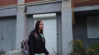  Sırt çantalı genç bir kadın şehirde yürüyor. 