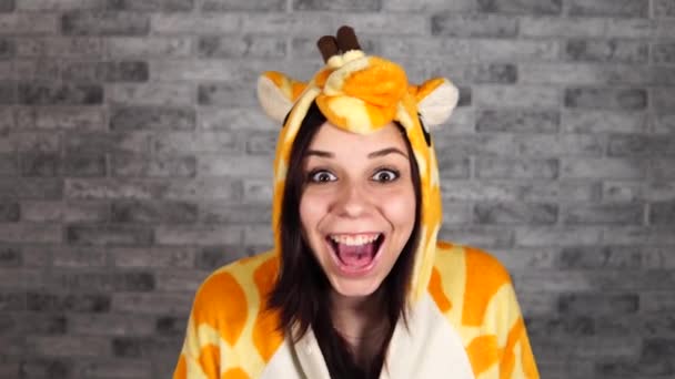 Pajamas in the form of a giraffe. emotional portrait of a woman on a gray brick background . crazy and funny man in a suit. animator for childrens parties. Halloween party costume — Stock Video