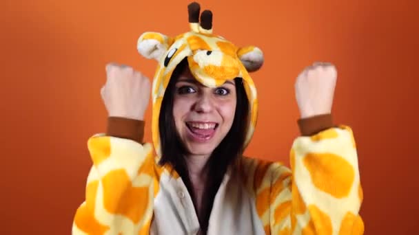 Pajamas en forma de jirafa. retrato emocional de una mujer en un fondo naranja. Un hombre loco y divertido en un traje. animador para fiestas infantiles. Ropa de fiesta de Halloween — Vídeo de stock