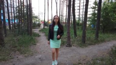 Genç bir kadın parkta yürüyor.