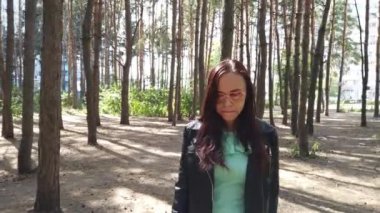 Genç bir kadın parkta yürüyor.