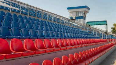 Spor stadyumundaki tribünler. Büyük bir stadyumda kırmızı ve mavi koltuklar.