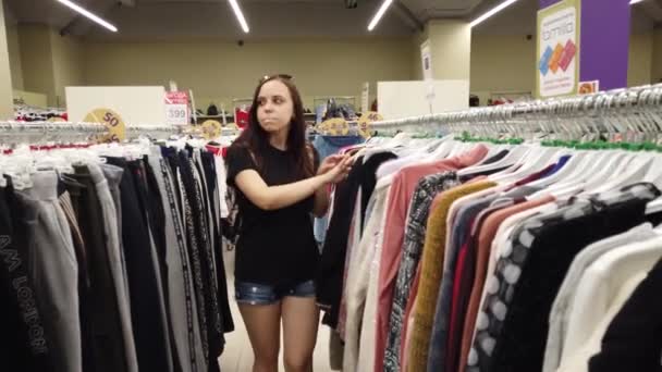Dziewczyna Sklepie Szuka Ubrań Kupienia Młoda Kobieta Kupuje Ubrania — Wideo stockowe