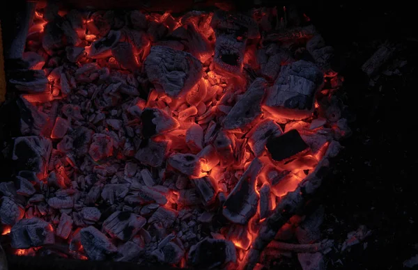 Kömür yangınının dokusu. Aktif olarak yanan ateş közleri. Yanan kömürlerin arka planı. Geceleri yanan kömürlerin titreşimi