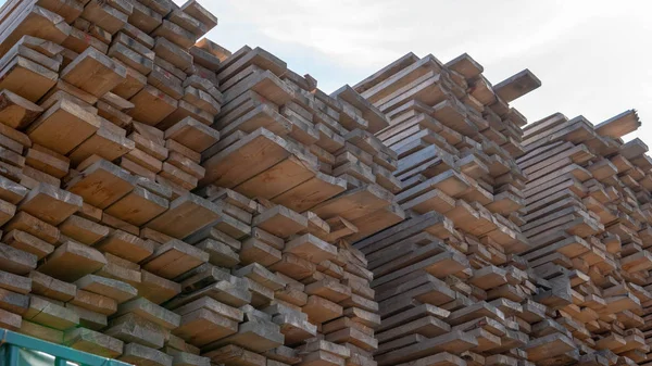 Wooden boards, lumber, industrial wood, timber. Pine wood timber stack of natural rough wooden boards on building site. Industrial timber building materials