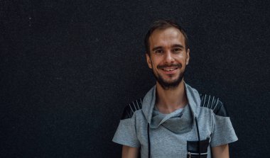 Yakışıklı bir adam siyah arka planda gülümser. Siyah arka planda gülümseyen yakışıklı sakallı hippi portresi. Kameraya bakan mutlu genç adam. Metin için alanı kopyala.