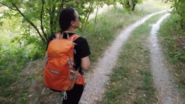 Sırt çantalı genç bayan turist dışarıda yürüyor.