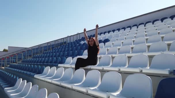 Siyah Elbiseli Uzun Saçlı Genç Bir Kadın Stadyumda Oturuyor — Stok video