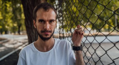 Parktaki tel örgülerin yanında sakallı yakışıklı bir adamın portresi..