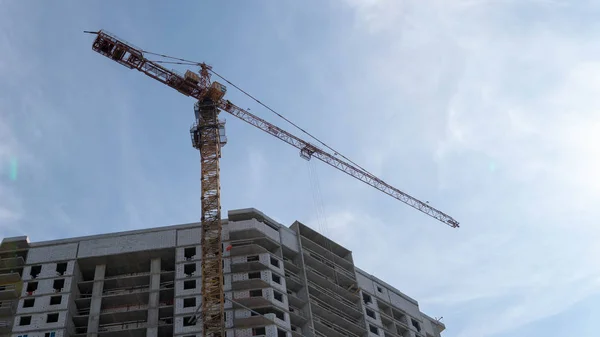 Edificio moderno en construcción con grúa. Desde abajo de la construcción de edificios con grúa alta bajo el cielo despejado —  Fotos de Stock