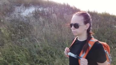 Sırt çantalı genç bayan turist dışarıda yürüyor.