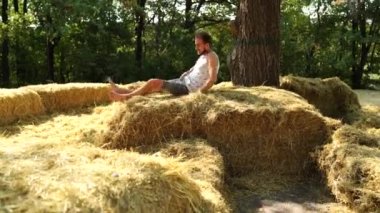 Güneşli bir günde samanlıkta ince sakallı yakışıklı bir adam.