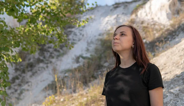 Uma jovem bonita em roupas pretas contra as montanhas brancas giz. — Fotografia de Stock