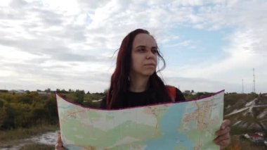 Sırt çantası elinde harita olan kadın.