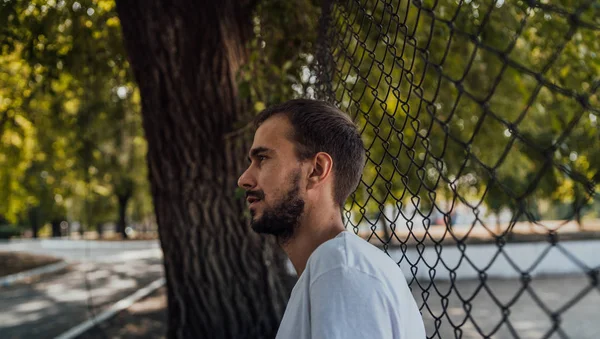 Parktaki tel örgülerin yanında sakallı yakışıklı bir adamın portresi..