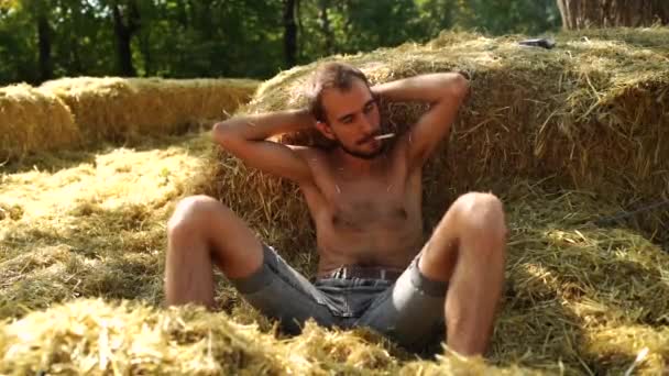 英俊男子在干草中抽烟 — 图库视频影像