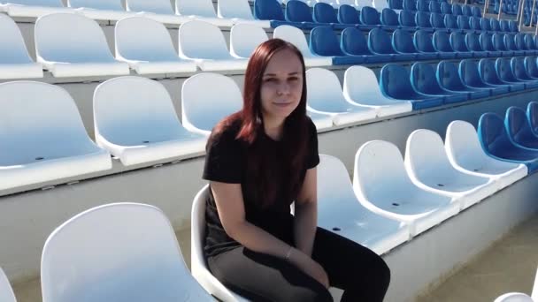 Молодая Женщина Черной Одежде Длинными Волосами Сидит Стадионе — стоковое видео