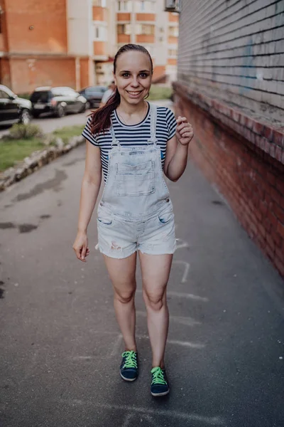 Egy fiatal nő alkalmi ruhában áll és mosolyog az utcán nyáron.. — Stock Fotó