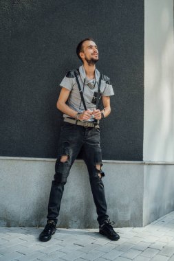 Sıradan giysiler içinde sakallı genç yakışıklı bir adam sokak duvarına karşı poz veriyor.