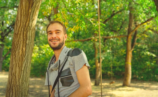 Um retrato de um homem bonito com barba no fundo de árvores verdes no parque . — Fotografia de Stock