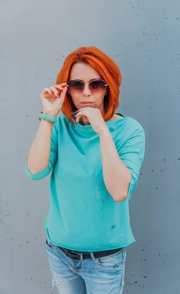 Retrato de jovem ruiva em roupas casuais e com óculos de sol . — Fotografia de Stock