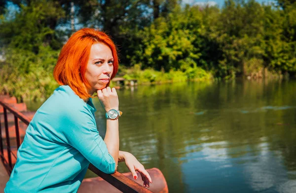 Portrait d'une femme adulte aux cheveux rouges en tenue décontractée se tenant sur le pont — Photo