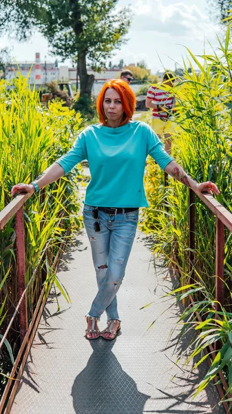 El retrato de una mujer adulta de pelo rojo con ropa ocasional se encuentra en el puente. — Foto de Stock