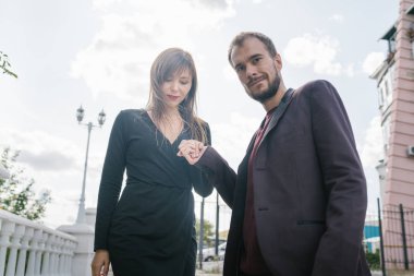 Mutlu çift. Şehirde yürüyüş yapmak. Genç çift uzun elbiseli bir kadını kucağında tutuyor. Güzel, şık bir çift Avrupalı şehrin sokaklarında yürüyor..