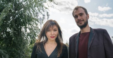 Mutlu çift. Şehirde yürüyüş yapmak. Genç çift uzun elbiseli bir kadını kucağında tutuyor. Güzel, şık bir çift Avrupalı şehrin sokaklarında yürüyor..