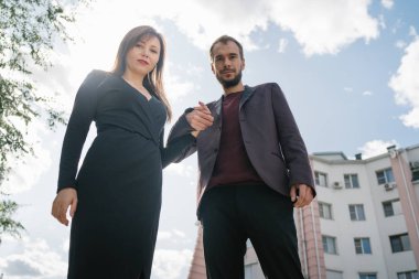 Mutlu çift. Şehirde yürüyüş yapmak. Genç çift uzun elbiseli bir kadını kucağında tutuyor. Güzel, şık bir çift Avrupalı şehrin sokaklarında yürüyor..