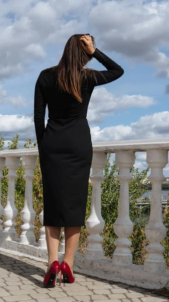 Красива жінка в чорній сукні стоїть на набережній влітку . — стокове фото