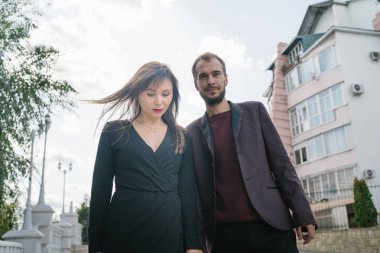 Mutlu çift. Şehirde yürüyüş yapmak. Genç çift uzun elbiseli bir kadını kucağında tutuyor. Güzel, şık bir çift Avrupalı şehrin sokaklarında yürüyor..