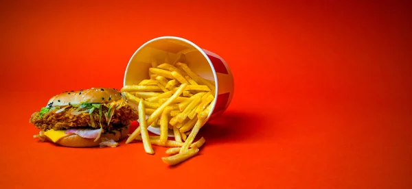 Burger ve patates kızartması turuncu arka planda izole edilmiş. Fast food restoranından yağlı burger ve patates kızartması turuncu arka planda izole edilmiş.