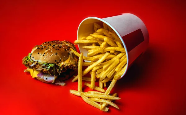 Burger ve patates kızartması turuncu arka planda izole edilmiş. Fast food restoranından yağlı burger ve patates kızartması turuncu arka planda izole edilmiş.