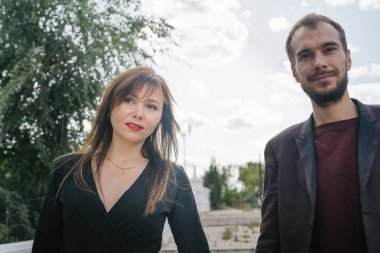 Mutlu çift. Şehirde yürüyüş yapmak. Genç çift uzun elbiseli bir kadını kucağında tutuyor. Güzel, şık bir çift Avrupalı şehrin sokaklarında yürüyor..