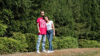 Güneşli bir bahar parkında hamburger yiyen bir kadın. Sunny Day 'li genç bir kadın sonbahar ormanında hamburger yiyor..