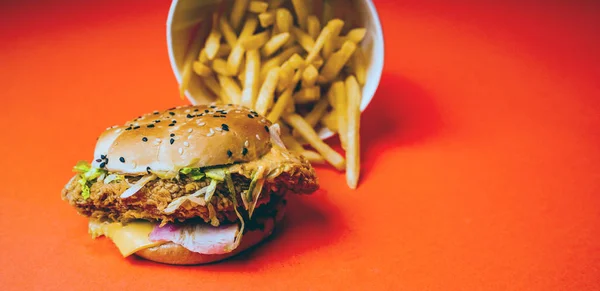 Hamburguesa y papas fritas Aisladas sobre un fondo naranja. Hamburguesa grasosa y papas fritas de un restaurante de comida rápida aislado sobre un fondo naranja, espacio para copiar —  Fotos de Stock