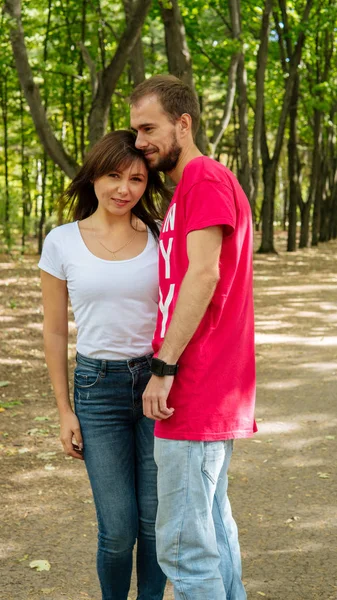 Ein verliebtes Paar umarmt und posiert vor dem Hintergrund blühender Bäume und Sträucher. Junge Kerle und Mädchen vor dem Hintergrund eines blühenden Parks — Stockfoto