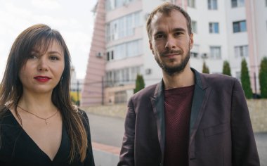 Mutlu çift. Şehirde yürüyüş yapmak. Genç çift uzun elbiseli bir kadını kucağında tutuyor. Güzel, şık bir çift Avrupalı şehrin sokaklarında yürüyor..