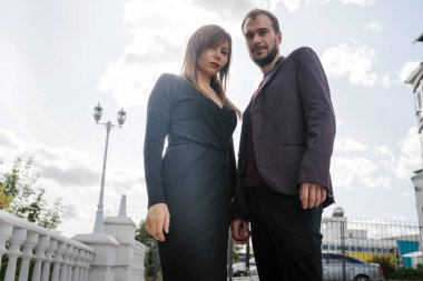 Mutlu çift. Şehirde yürüyüş yapmak. Genç çift uzun elbiseli bir kadını kucağında tutuyor. Güzel, şık bir çift Avrupalı şehrin sokaklarında yürüyor..