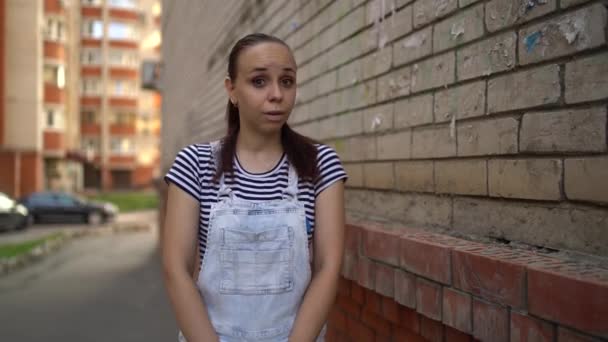 Une jeune femme en tenue décontractée se tord devant son temple dans la rue. — Video